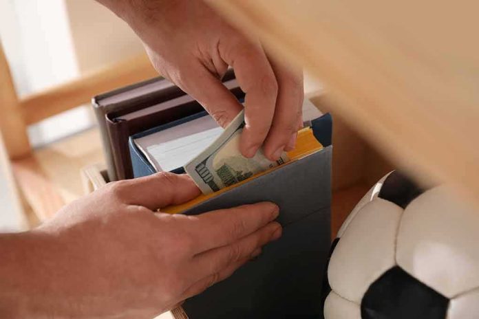 shutterstock_1640830765 Hands hiding cash inside a book on a shelf