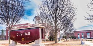 Democrat Mayor ACCUSED Of Scandalous Behavior City Hall sign in front of a red-brick municipal building