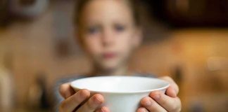 Child holding a white bowl toward the camera