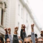 Socialist Candidates’ BRAZEN Grab Hits Close To Home Group of people raising clenched fists at a street protest