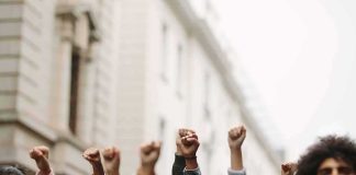 Socialist Candidates’ BRAZEN Grab Hits Close To Home Group of people raising clenched fists at a street protest