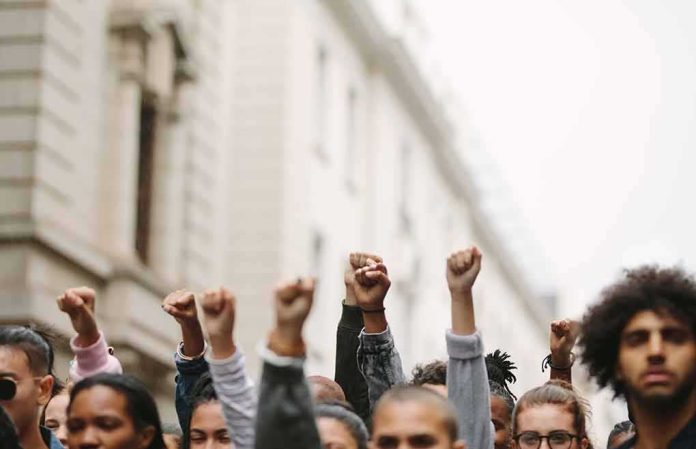 shutterstock_1736459849 Group of people raising clenched fists at a street protest