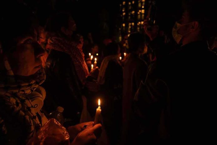 shutterstock_2376401551 People holding candles at a nighttime vigil