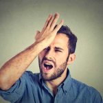 Man with hand on forehead expressing frustration