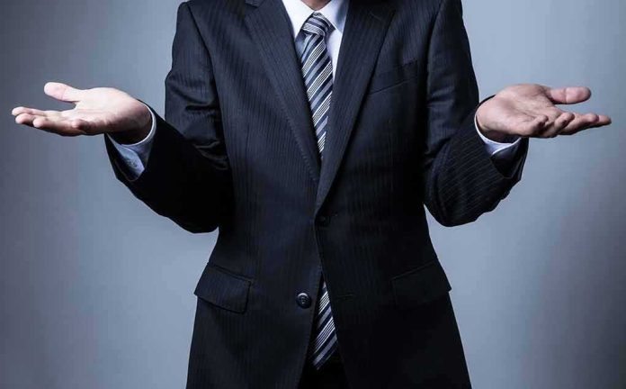 shutterstock_499983775-1 Businessperson in suit shrugging with open hands