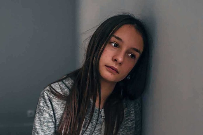 Teen girl leaning against a wall with a pensive expression